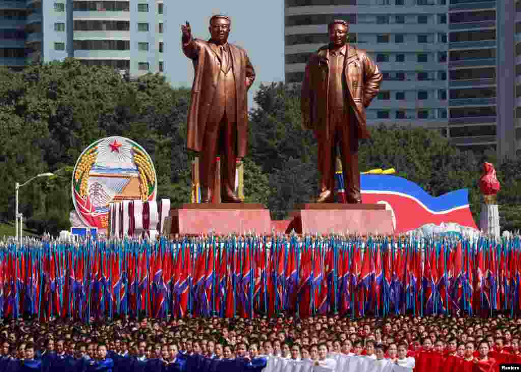 People carry flags in front of statues of North Korea founder Kim Il Sung, left, and late leader Kim Jong Il during a military parade marking the 70th anniversary of North Korea's foundation in Pyongyang, North Korea, Sept. 9, 2018.