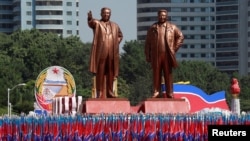 People carry flags in front of statues of North Korea founder Kim Il Sung, left, and late leader Kim Jong Il during a military parade marking the 70th anniversary of North Korea's foundation in Pyongyang, North Korea, Sept. 9, 2018.