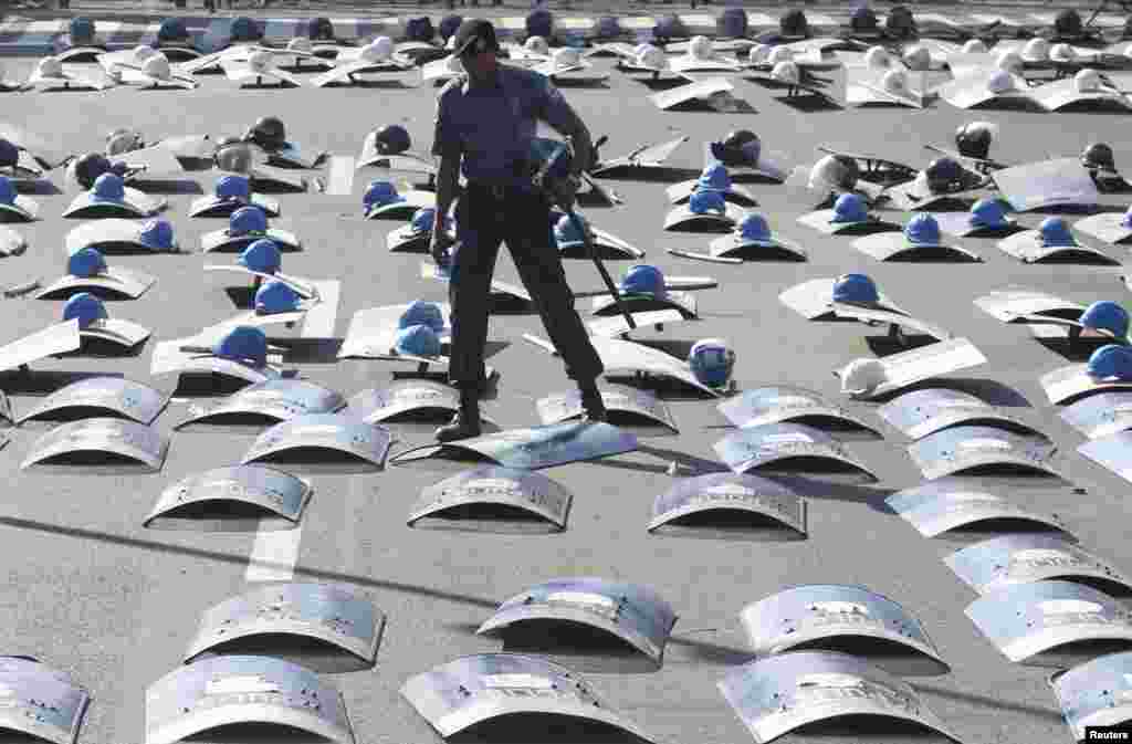 A policeman aligns his shield on the pavement as they wait for protesters to march during International Labor Day near the Malacanang Palace in Manila, Philippines. 