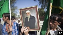 A supporter of Burhanuddin Rabbani, former Afghanistan president and head of the government's peace council, holds his picture while standing outside his house a day after he was killed in Kabul September 21, 2011.