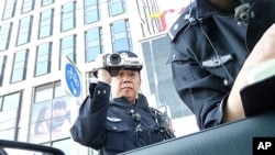 Police officers filming and checking VOA reporter's documents as he tried to get close to the site of the banned Easter service in Beijing, April 24, 2011