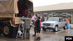 Trestian Woodard, 7, finds welcoming arms at a gas station doubling as a rescue transfer point in north Houston, Aug. 27, 2017. National Guard and Aldine Fire & Rescue members collected people from the Greenbriar Colony neighborhood. (C. Mendoza/VOA)