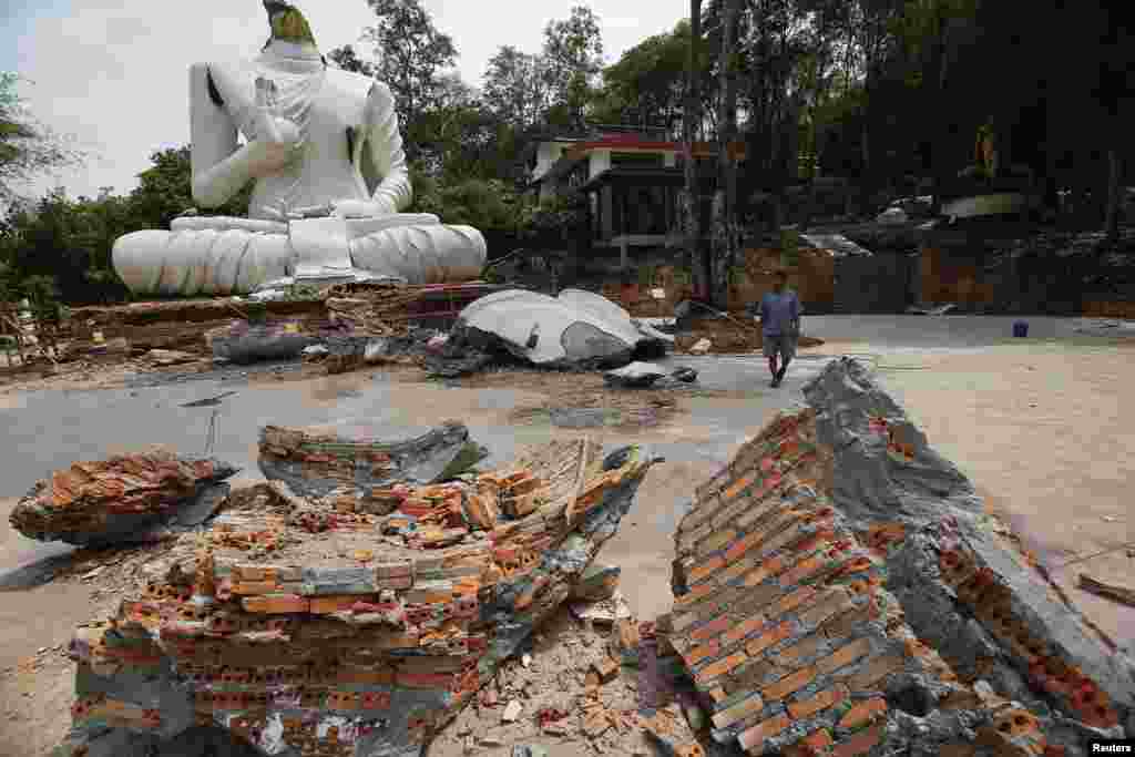 Seorang warga berjalan di depan patung Buddha yang rusak akibat gempa bumi di kuil Udomwaree di Chiang Rai, Thailand utara, 6 Mei 2014.