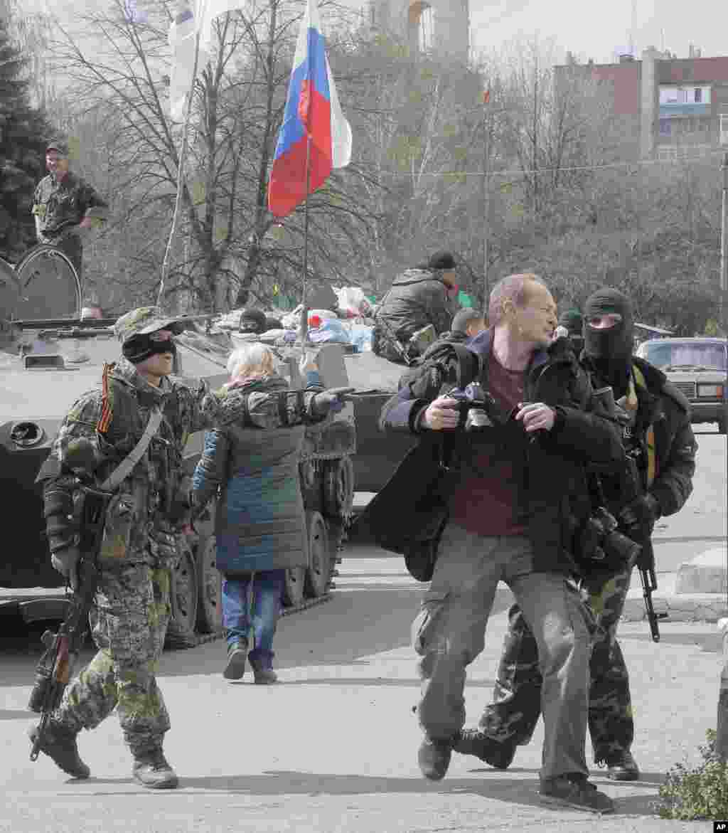 Masked pro-Russian gunmen attack a photojournalist near combat vehicles flying a Russian flag, in Slovyansk, Ukraine, April 16, 2014. 