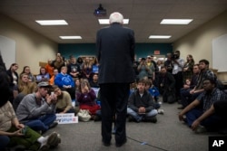 People look on as Democratic presidential candidate Sen. Bernie Sanders of Vermont speaks during a meeting with volunteers at a canvass lunch at Wartburg College in Waverly, Iowa, Jan. 30, 2016.