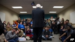 People look on as Democratic presidential candidate Sen. Bernie Sanders of Vermont speaks during a meeting with volunteers at a canvass lunch at Wartburg College in Waverly, Iowa, Jan. 30, 2016. 