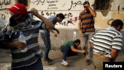 FILE - Members of the Muslim Brotherhood and supporters of ousted Egyptian president Mohamed Morsi react to tear gas released on them by riot police during clashes near Cairo's Tahrir Square October 6, 2013.