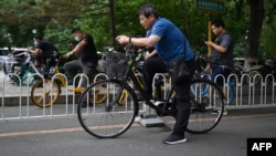 资料照片: 2021年7月1日北京街頭騎行者用手機觀看現場直播