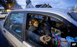 Paige Clem sits in the car she lives in along with her husband and three dogs outside a church where free food was being distributed in Everett, Washington, Oct. 12, 2017.