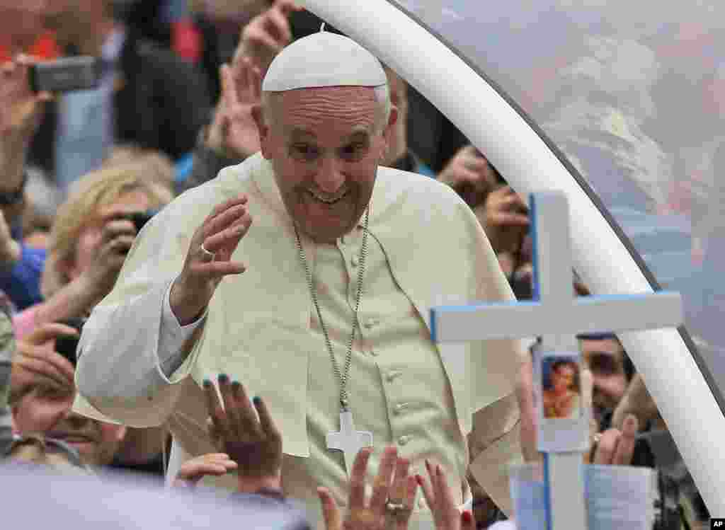 Paus Fransiskus melambaikan tangan pada umat ketika melewati kerumunan setelah memimpin upacara kanoninasi di Lapangan Santo Petrus, Vatikan, 27 April 2014.