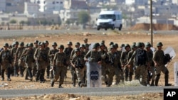 Turkish soldiers take their position a few hundreds meters from the the Turkey-Syria border in Mursitpinar, near Suruc, as fighting intensified between Syrian Kurds and the militants of Islamic State, Oct. 5, 2014.