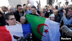 Muslims, holding French and Algerian flags, attend a gathering in front of the Paris Mosque after Friday prayers September 26, 2014, to pay tribute to Herve Gourdel, a French mountain guide who was beheaded by an Algerian Islamist group.
