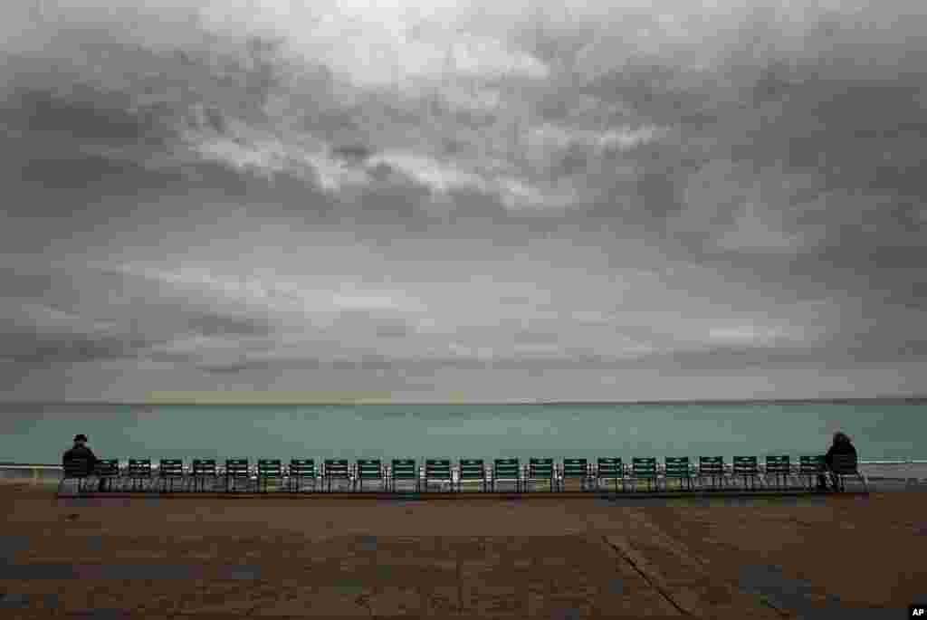 People look at the Mediterranean Sea from La Promenade des Anglais on a rainy day, in Nice, southeastern France. Temperatures on the French Riviera reached 9 degrees Celsius (48 Fahrenheit).