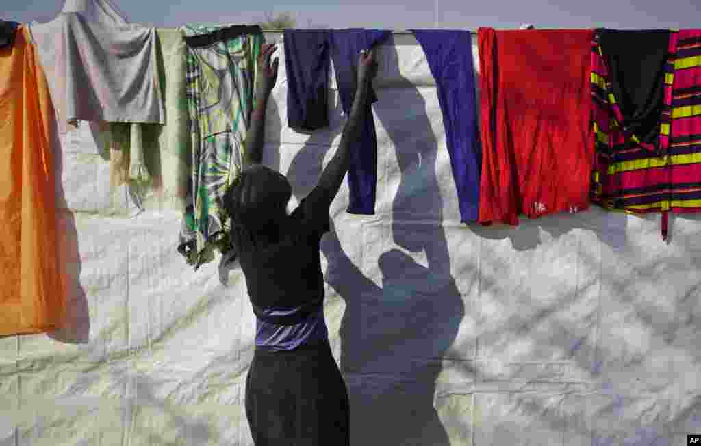 A displaced woman hangs up laundry on the plastic sheeting wall of a latrine at a United Nations compound, Juba, South Sudan, Dec. 31, 2013.