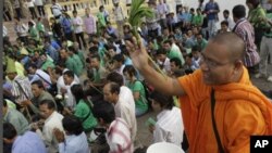 A Cambodian Buddhist monk sprinkles holly water to villagers who set a prayer rally to save rain forests in front of Royal Palace in Phnom Penh, Cambodia, Thursday, Aug. 18, 2011. Hundreds of villagers prayed at the spirit's shrine, demanding the governme