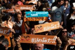 FILE - Protesters holds banners that read in Catalan '' freedom'' showing the portraits of the inprisoned Jordi Sanchez and Jordi Cuixart, leaders of the Catalan grassroots organizations Catalan National Assembly and Omnium Cultural, during a rally outside the Catalan parliament in Barcelona, Spain, Oct. 27, 2017.