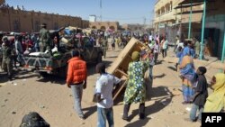 Malian troops try to dissuade the crowd from looting shops in Timbuktu, Jan. 29, 2013. Hundreds of Malians looted Arab-owned shops Tuesday in Mali's fabled Timbuktu, newly freed from Islamists. 