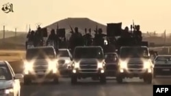 FILE - An image grab taken from a video released by Islamic State group's official Al-Raqqa site via YouTube allegedly shows Islamic State (IS) group recruits riding in armed trucks in an unknown location. 