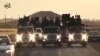 FILE - An image grab taken from a different video, released by the Islamic State group's official Al-Raqqa site via YouTube, allegedly shows IS recruits riding in trucks in an unknown location. 