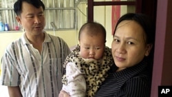 Taiwanese security guard Huang Chin-tsai, 44, looks at his his wife, Vu Thi Minh, 30, from Vietnam and their six-month-old daughter in their home, in Wanli, 30 miles north of Taipei, Taiwan, March 1, 2003.