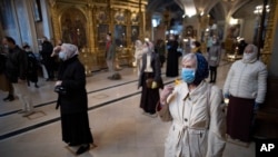 Parishioners wearing face masks to protect against coronavirus observe social distancing guidelines as they cross themselves at the Epiphany Cathedral in Moscow, Russia, June 2, 2020. 