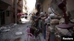 A Free Syrian Army fighter points his weapon as he takes up position behind sandbags in Deir al-Zor, Syria, July 13, 2013. 