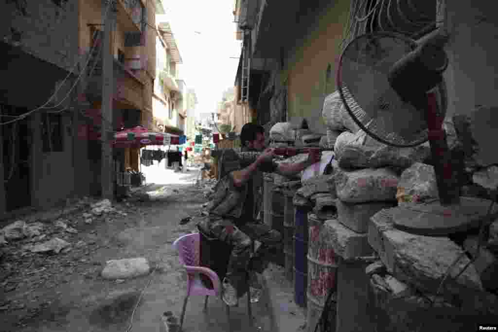 A Free Syrian Army fighter points his weapon as he takes up position behind sandbags in Deir al-Zor, Syria, July 13, 2013. 