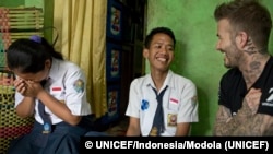 FILE - UNICEF Goodwill Ambassador David Beckham smiles with Sripun, 15, left, and her friend Ego, center, in Semarang, Indonesia, March 27, 2018. Beckham met with students as part of a UNICEF anti-bullying program. 