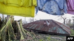 Anak-anak duduk di atas atap rumah yang diterbangkan topan Koppu di kota Casiguran, provinsi Auroran, sebelah timur laut Manila, Filipina (21/10). (AFP/Dante Diosina)