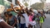 ARCHIVO - Vecinos huyen de sus casas durante los enfrentamientos entre la policía y miembros de una pandilla en el barrio de Portail en Puerto Príncipe, Haití, el jueves 29 de febrero de 2024.