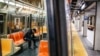 A subway customer wears protective gloves on an empty car as it stops at a sparsely populated 57th Street station due to COVID-19 concerns, March 20, 2020, in New York. 