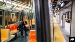 A subway customer wears protective gloves on an empty car as it stops at a sparsely populated 57th Street station due to COVID-19 concerns, March 20, 2020, in New York. 