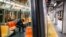 A subway customer wears protective gloves on an empty car as it stops at a sparsely populated 57th Street station due to COVID-19 concerns, March 20, 2020, in New York. 