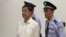 In this image taken from video, disgraced politician Bo Xilai, center, enters the courtroom, flanked by police guards at Jinan Intermediate People's Court in eastern China's Shandong province, Aug. 22, 2013. 