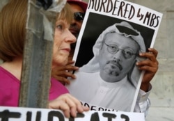 FILE - In this Oct. 10, 2018 photo, people hold signs during a protest at the Embassy of Saudi Arabia about the disappearance of Saudi journalist Jamal Khashoggi, in Washington.