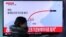 Una mujer en una estación de tren en Seúl, Corea del Sur, pasa frente a una pantalla de televisión donde se ve uninforme sobre la prueba misilística norcoreana el lunes, 6 de marzo, de 2017.
