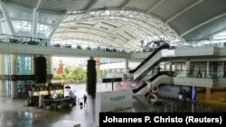 Seorang traveler berjalan menyusuri terminal kedatangan internasional yang hampir kosong dari bandara Gusti Ngurah Rai di tengah penyebaran Covid-19 di Bali, 1 April 2020. (Foto: REUTERS/Johannes P. Christo)