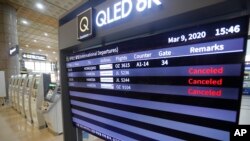 An electronic signboard shows that flights from Tokyo's Haneda airport scheduled were canceled near the self check-in system at Gimpo Airport in Seoul, South Korea, Monday, March 9, 2020.