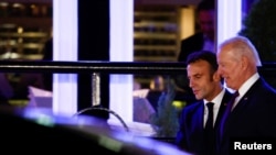 U.S. President Joe Biden and French President Emmanuel Macron walk next to a vehicle as they meet for dinner at Fiola Mare restaurant in the Georgetown neighborhood of Washington, Nov. 30, 2022.