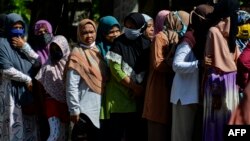 Sejumlah perempuan menggunakan masker wajah antre membeli sembako murah di Banda Aceh, 14 Mei 2020. (Foto: AFP)