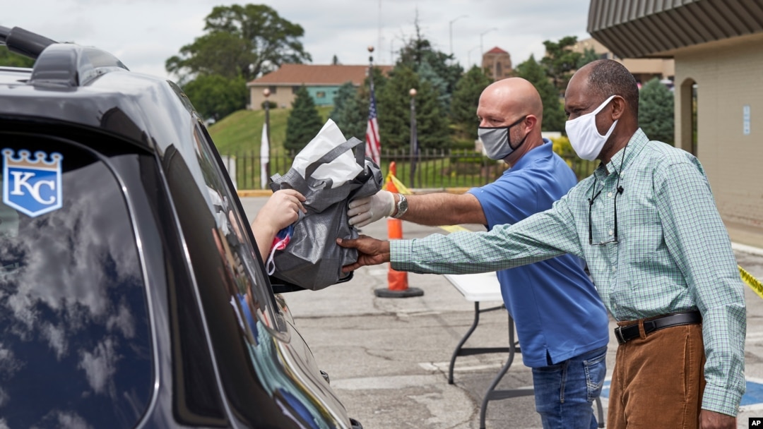 Čovek u automobilu prima paket sa informacijama o otvorenim pozicijama u drajv-in sajmu zapošljavanja u Omahi, Nebraska, 15. jula 2020.