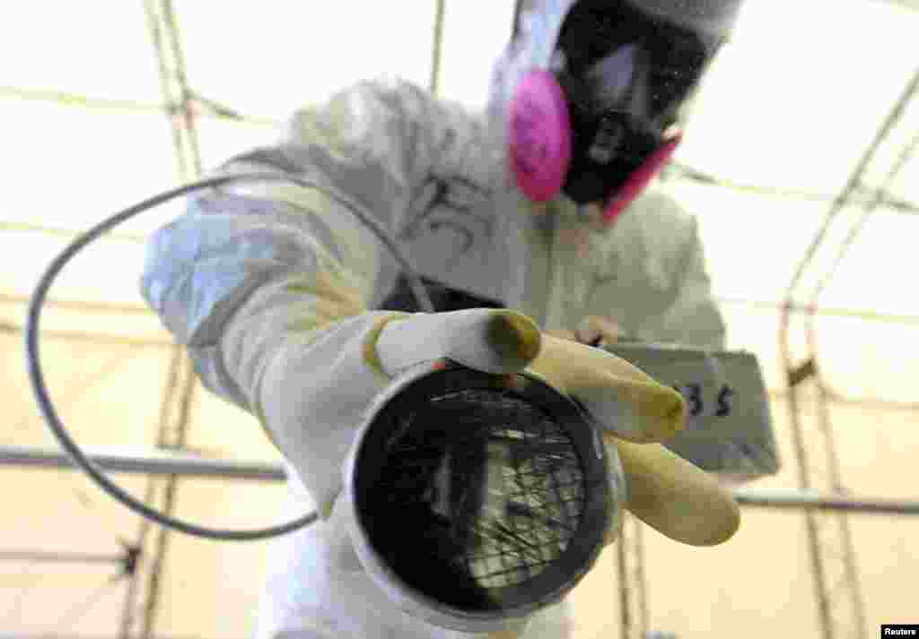 A worker takes radiation readings on the window of a bus at the screening point of the Fukushima Daiichi nuclear power plant, June 12, 2013. 