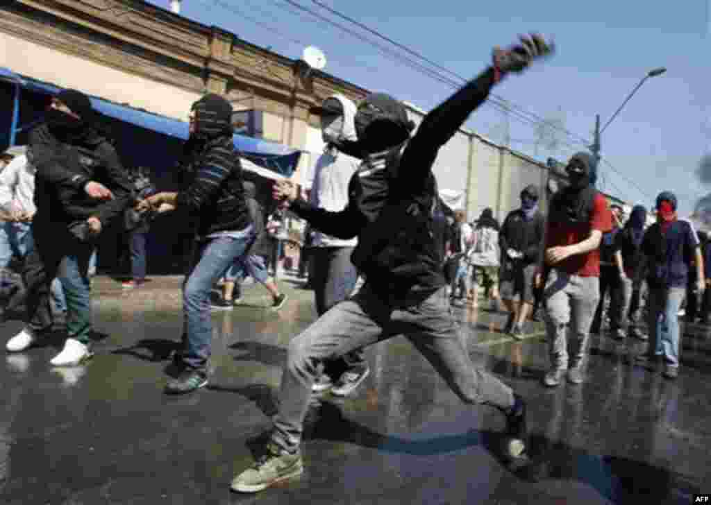 Demonstrators throws stones against anti-riot police after a march marking the 38th anniversary of Augusto Pinochet's military coup in Santiago, Chile, Sunday, Sept. 11, 2011. Pinochet assumed power on Sept. 11, 1973, in a coup supported by the United Sta