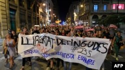 People hold a banner reading "release the prisoners" as they walk towards police headquarters in Barcelona on Sept. 26, 2019, during a protest against the detention of seven alleged radical militants.