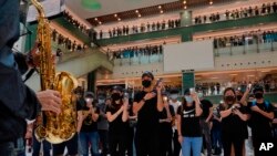Protesters wearing masks in defiance of a recently imposed ban on face coverings perform at a shopping mall in Hong Kong, Oct.13, 2019.