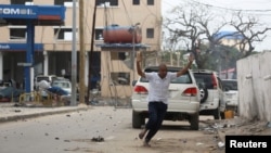 A man raises his hands as he runs from the scene of a suicide bomb attack outside the Hotel Naso-Hablod in Somalia's capital, Mogadishu, June 25, 2016.