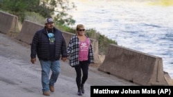 Molli Myers and her husband, Frankie, hold hands on Aug. 28, 2024, as they watch crews work to remove the final cofferdam that was left of Iron Gate Dam, allowing the Klamath River to flow through near Hornbrook, California. (Matthew Johan Mais via AP)