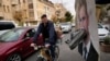 A cyclist rides past a portrait of ousted Syrian President Bashar al-Assad with a shoe attached to it as a sign of disdain, in Damascus, Syria, Dec. 23, 2024. 