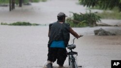 Un hombre camina con su bicicleta a través de inundaciones hasta las rodillas en un vecindario de Jehova, Honduras, el miércoles 4 de noviembre de 2020. Eta se debilitó de huracán de categoría 4 a tormenta tropical.