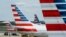 FILE - A member of a ground crew walks past American Airlines planes parked at the gate during the coronavirus outbreak at Ronald Reagan National Airport in Washington, April 5, 2020.